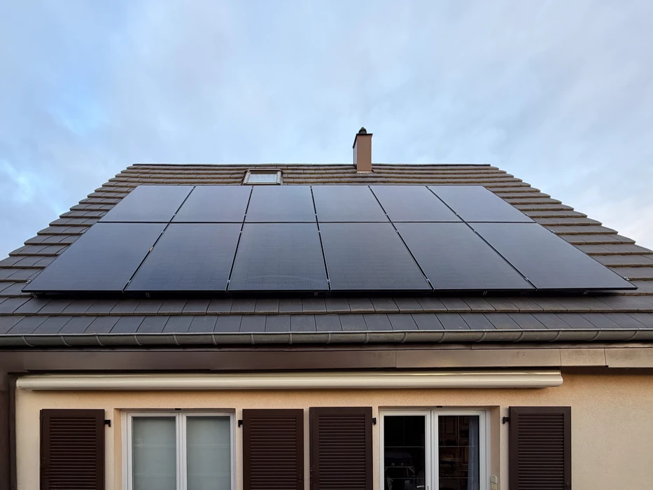 Maison résidentielle avec toiture équipée de panneaux solaires photovoltaïques noirs installés sur tuiles