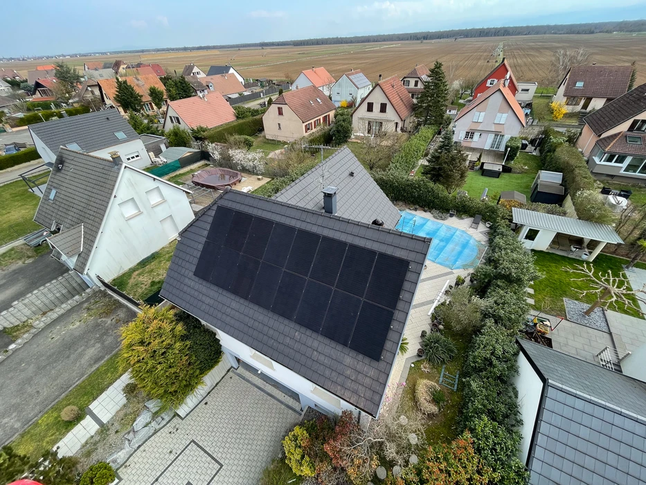 Extérieur résidentiel avec ouvrier installant des panneaux solaires photovoltaïques sur toiture en tuiles terre cuite